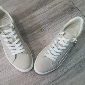 Paire de baskets beiges avec semelle blanche et lacets blancs.