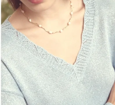 Femme portant un pull bleu clair à col V en maille brillante.