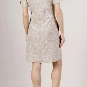 Vue de dos d’une femme portant une robe beige courte à manches courtes et motifs discrets.