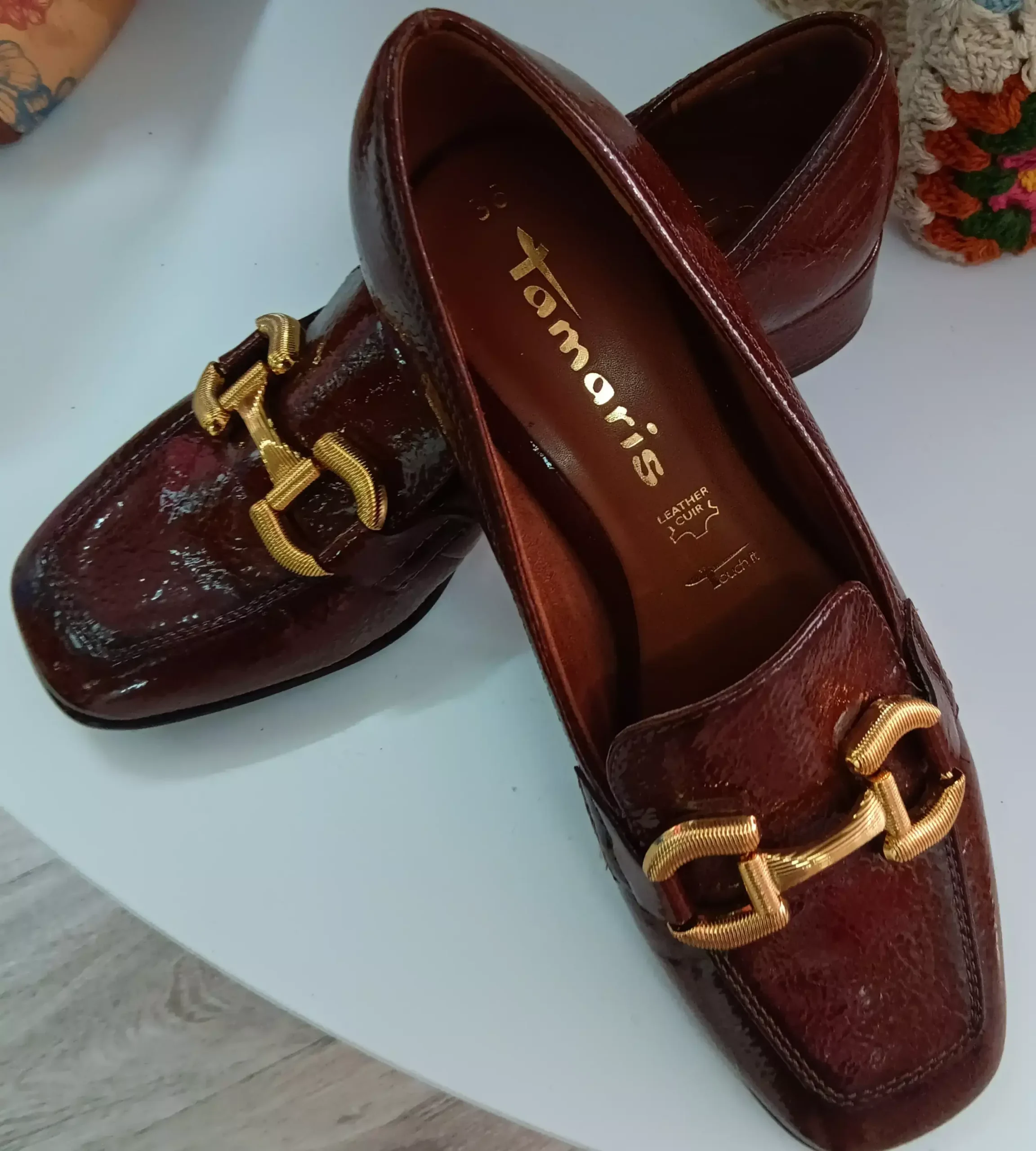 Paire de mocassins en cuir marron verni Tamaris avec boucle dorée.