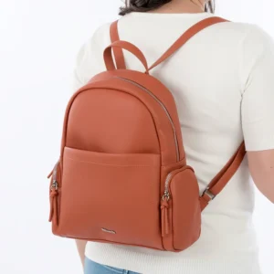 Sac à dos terracotta en simili cuir porté sur le dos d’une femme, avec poches zippées et design épuré.